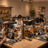 Team of artisans creating custom pet portraits by hand in a professional workshop while using pet reference photos displayed on tablets.