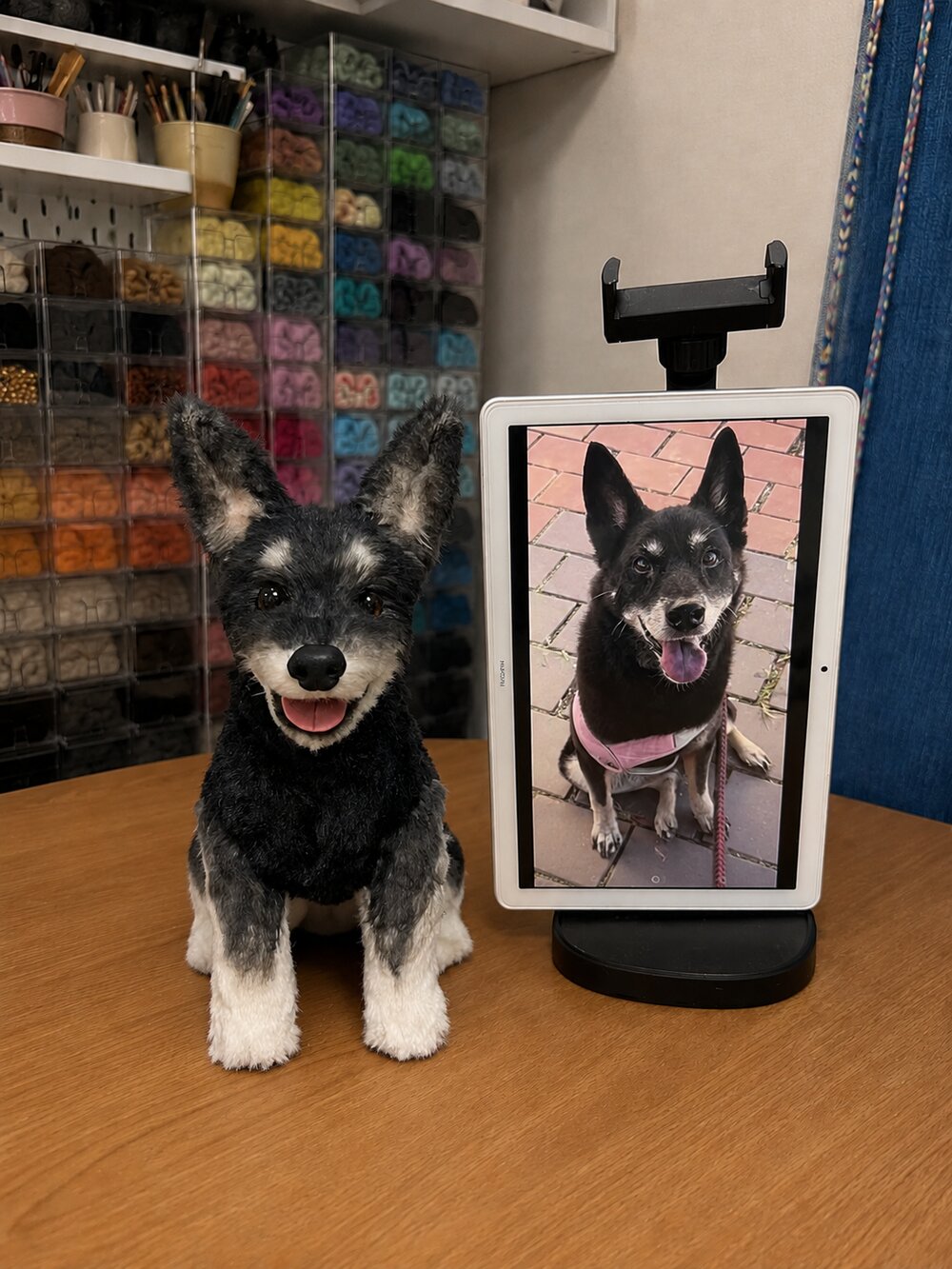 Handmade black and gray dog pet replica displayed beside the customer's reference photo on a tablet.