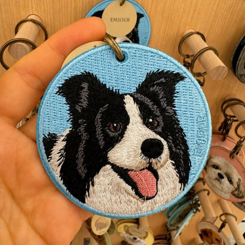 Custom round embroidered Border Collie portrait keychain featuring a black-and-white dog on a light blue fabric background.