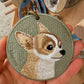Custom round embroidered Chihuahua portrait keychain featuring a tan-and-white dog on a muted green fabric background.
