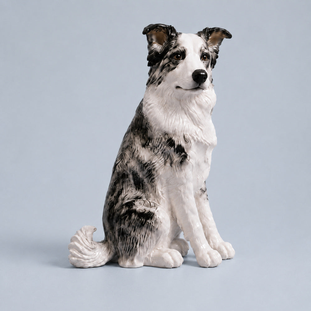 Custom glossy ceramic figurine of a seated black-and-white Border Collie displayed against a light blue studio background.