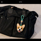 Personalized Corgi head charm with a green hanging loop attached to a black travel bag.