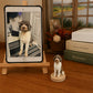 Custom brown and white curly-haired dog figurine displayed beside the pet’s reference photo on a tablet.