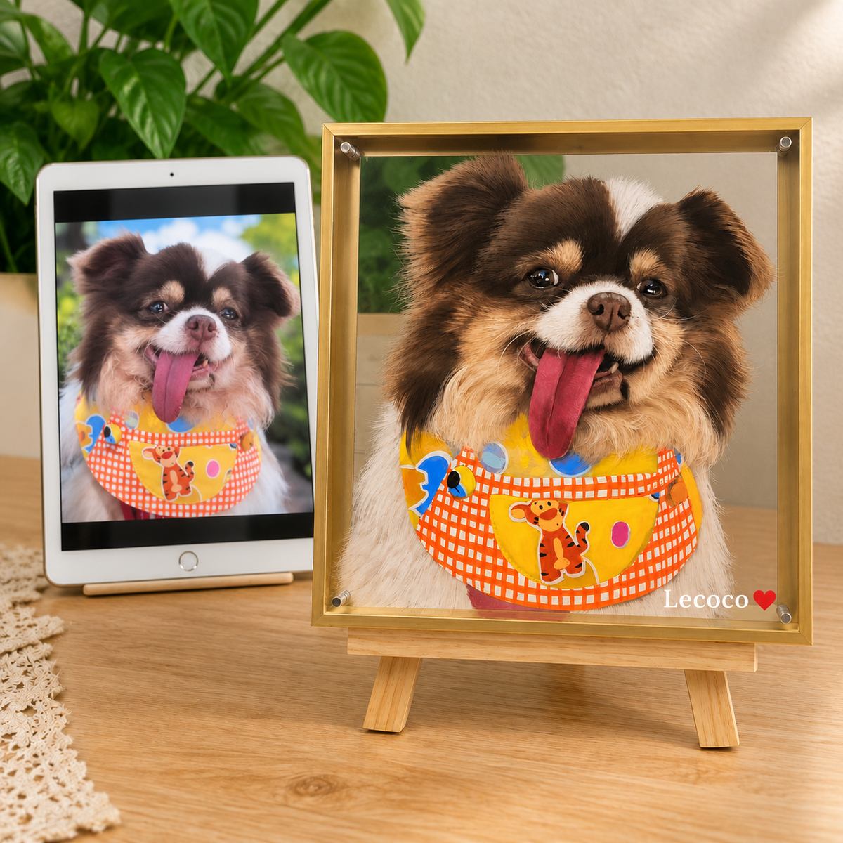 Lecoco's original dog photo on a tablet beside a personalized layered portrait in a gold frame, with a matching colorful bib.