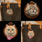 Two handcrafted round leather bag charms featuring personalized tabby and cream-colored cat portraits displayed on brown handbags.