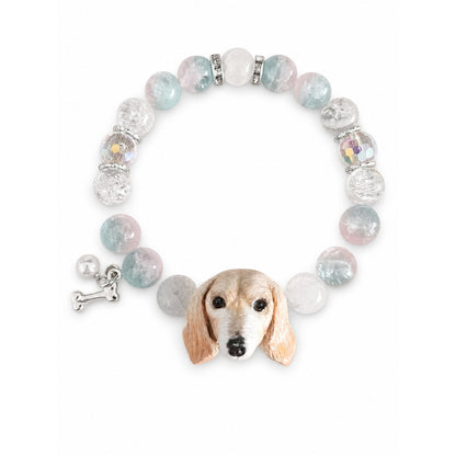 Handmade cream long-eared dog portrait bracelet with pale blue, pink and clear crystal beads on white.