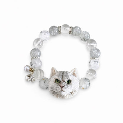 Custom silver-gray long-haired cat portrait bracelet with green eyes and clear beads on white.