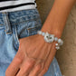 Personalized silver-gray long-haired cat portrait bracelet with green eyes, worn on the wrist.