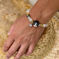 Personalized black-and-white folded-ear cat portrait bracelet worn with black, white and gold beads.