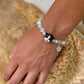 Personalized black-and-white folded-ear cat portrait bracelet worn with pastel crystal beads.