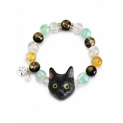 Handmade black cat portrait beaded bracelet with yellow, black and green crystal beads on white.