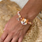Personalized orange-and-white fluffy dog portrait bracelet worn with peach crystal beads.