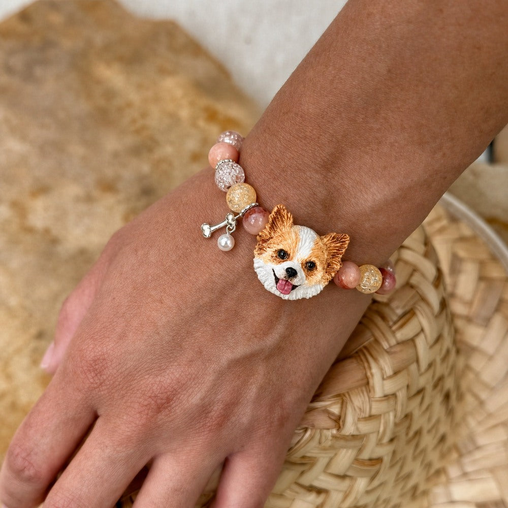 Personalized orange-and-white fluffy dog portrait bracelet worn with peach crystal beads.