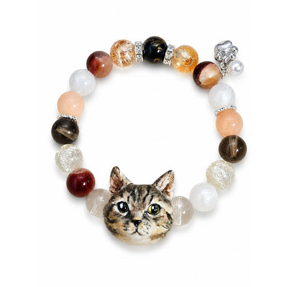 Handmade tabby cat portrait beaded bracelet with brown, white and peach crystal beads on white.