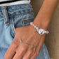 Personalized white upright-ear fluffy dog portrait bracelet worn with pastel pink crystal beads.