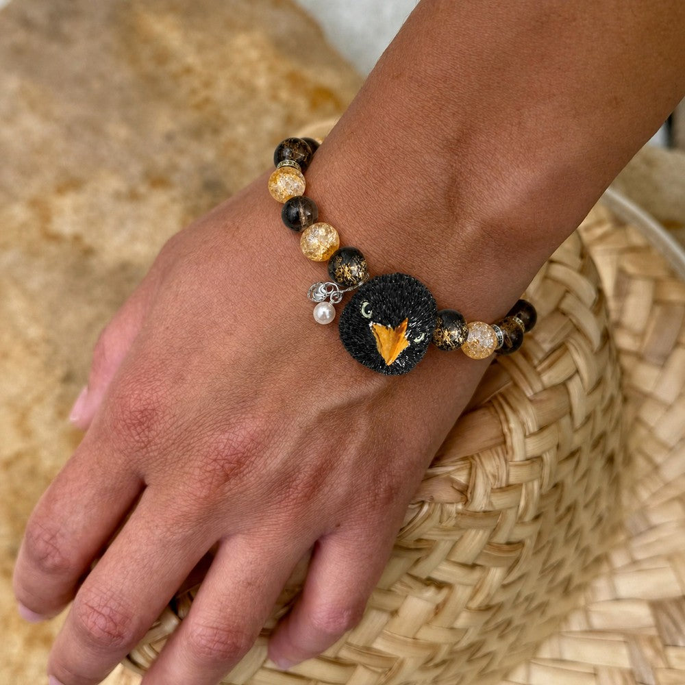 Personalized pet bird portrait bracelet worn on the wrist with black and amber crystal beads.