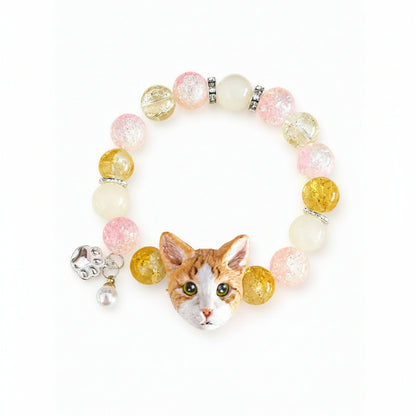 Custom orange-and-white cat portrait bracelet with yellow, pink and white crystal beads on a white background.