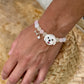 Personalized white fluffy dog portrait bracelet worn on the wrist with pale pink crystal beads.