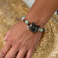Personalized black cat portrait beaded bracelet worn on the wrist with green and brown crystal beads.