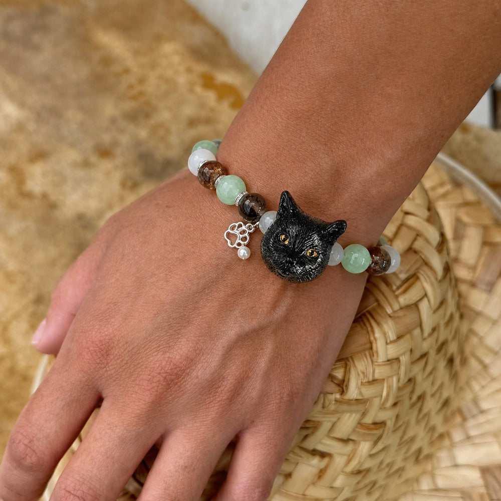Personalized black cat portrait beaded bracelet worn on the wrist with green and brown crystal beads.