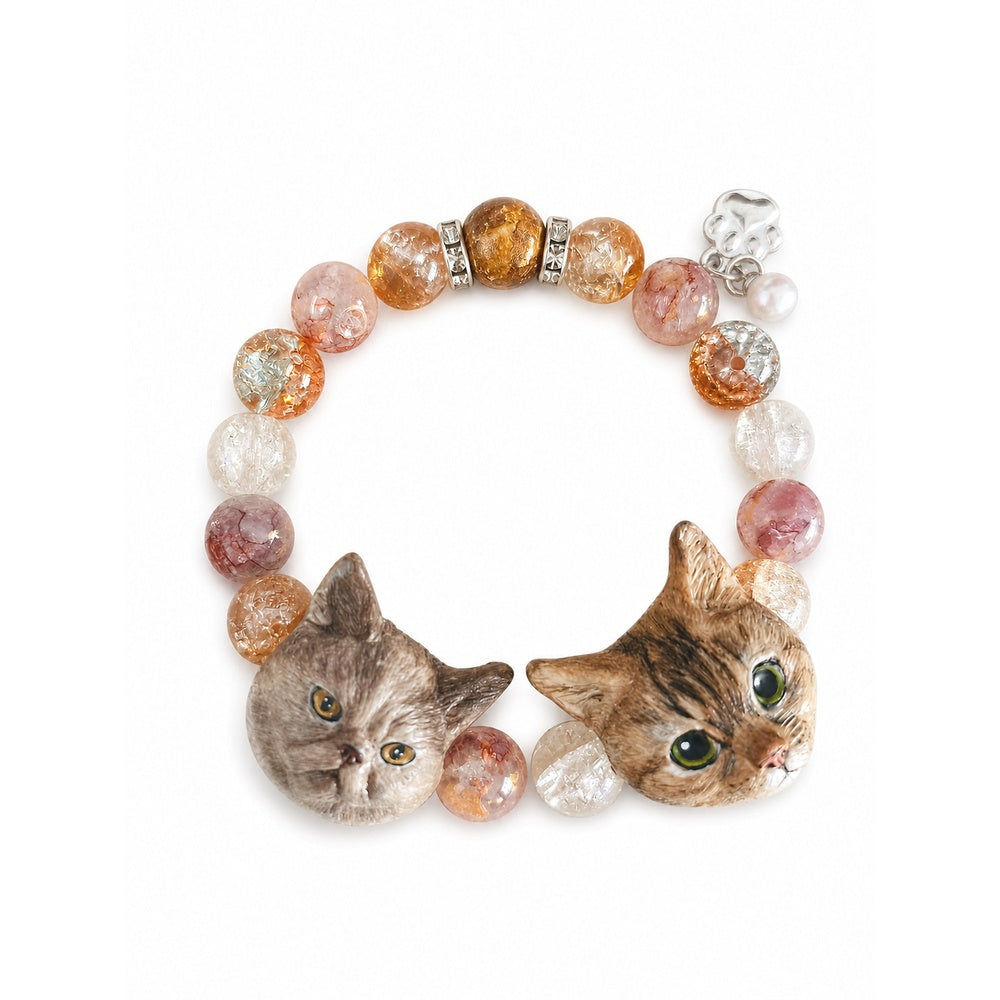 Handmade two-cat portrait bracelet with gray and brown tabby charms and warm crystal beads on white.