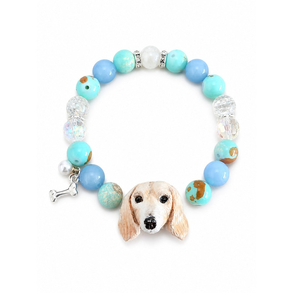Handmade cream long-eared dog portrait bracelet with blue, aqua and clear crystal beads on white.