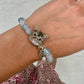 Custom tabby cat portrait crystal bracelet worn on the wrist with a hand-sculpted cat face charm and blue beads.