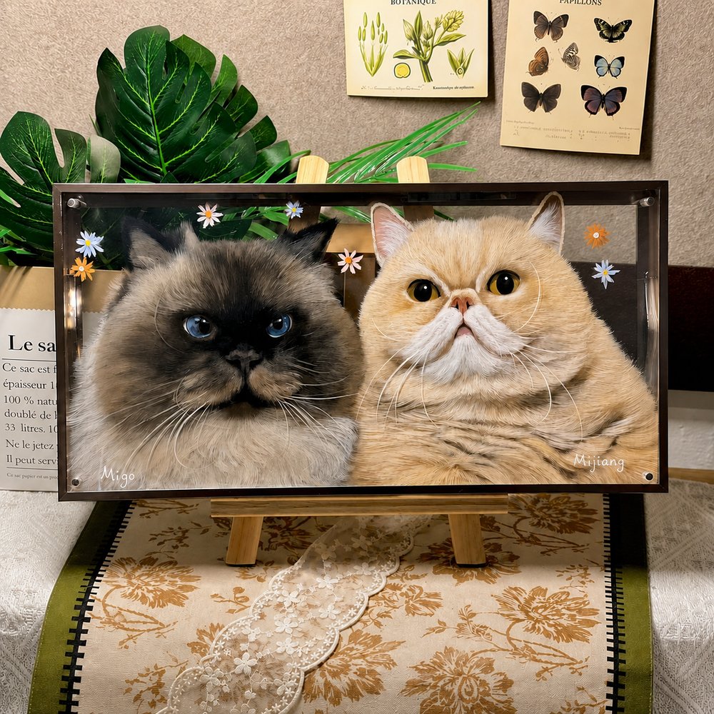 Custom glass pet portrait of a dark fluffy cat and a cream-colored cat, displayed in a decorative frame on a wooden easel.
