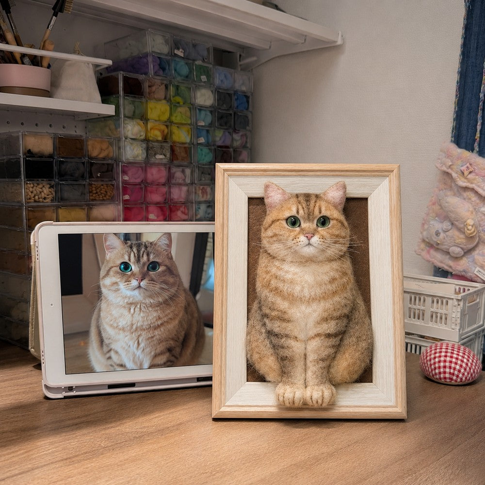 Handmade full-body 3D felt portrait of a golden tabby cat displayed in a natural wooden frame beside the cat’s reference photo.