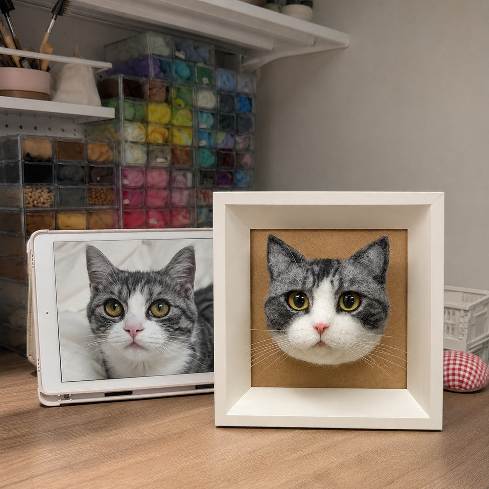Handmade 3D felt portrait of a gray and white tabby cat displayed in a white shadow box beside the pet’s reference photo.