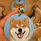 Custom round embroidered Shiba Inu portrait keychain featuring a smiling tan-and-white dog on a light blue fabric background.