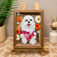 Custom glass pet portrait of a white Maltese named Nini wearing a pink bandana, surrounded by colorful flowers in a wooden frame.