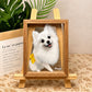 Custom glass pet portrait of a white Pomeranian named Mango displayed in a wooden frame on an easel.