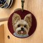 Custom round embroidered Yorkshire Terrier portrait keychain on a burgundy fabric background with antique brass-tone hardware.